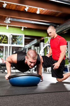 Photo of a male fitness trainer working on a male client. 